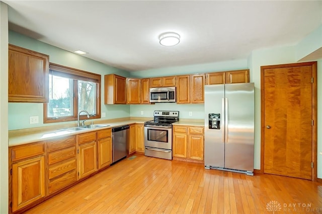 kitchen with appliances with stainless steel finishes, light hardwood / wood-style floors, and sink