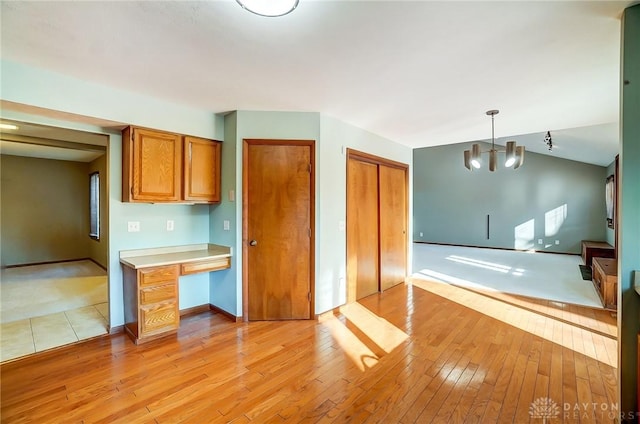 kitchen featuring decorative light fixtures, vaulted ceiling, light hardwood / wood-style flooring, and an inviting chandelier