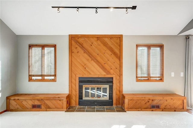 living room featuring lofted ceiling, a tile fireplace, track lighting, and a healthy amount of sunlight