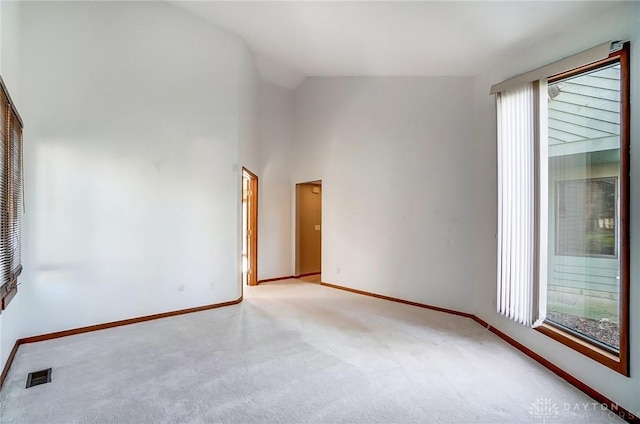 carpeted spare room featuring vaulted ceiling