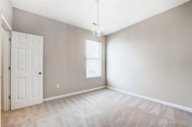 carpeted spare room with a chandelier