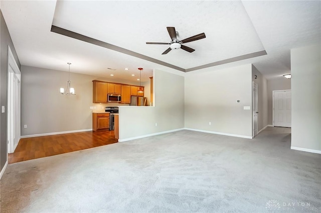 unfurnished living room with ceiling fan with notable chandelier and carpet floors