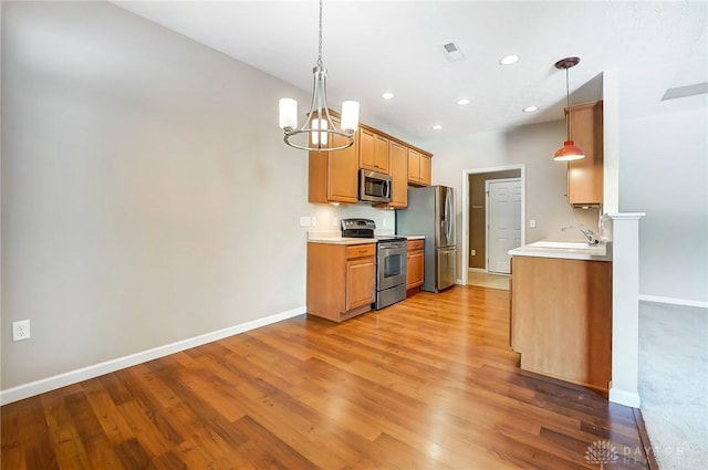 kitchen with hanging light fixtures, a chandelier, stainless steel appliances, and light hardwood / wood-style floors