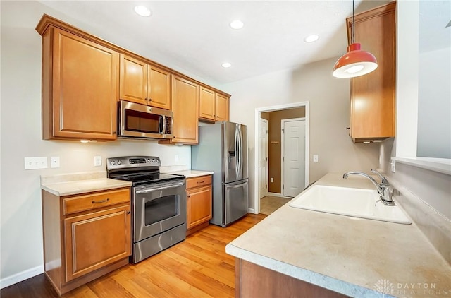 kitchen with light wood-type flooring, appliances with stainless steel finishes, and sink