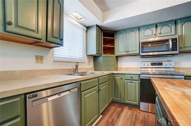 kitchen featuring wood counters, hardwood / wood-style floors, green cabinets, appliances with stainless steel finishes, and sink