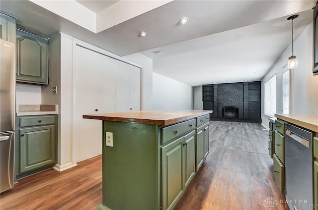 kitchen with decorative light fixtures, a fireplace, a kitchen island, appliances with stainless steel finishes, and butcher block counters