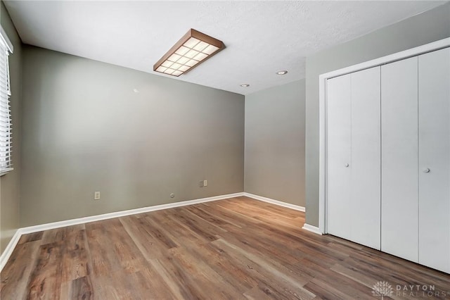 unfurnished bedroom featuring a closet, a textured ceiling, and hardwood / wood-style floors