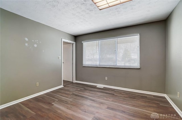 empty room with a textured ceiling and dark hardwood / wood-style floors