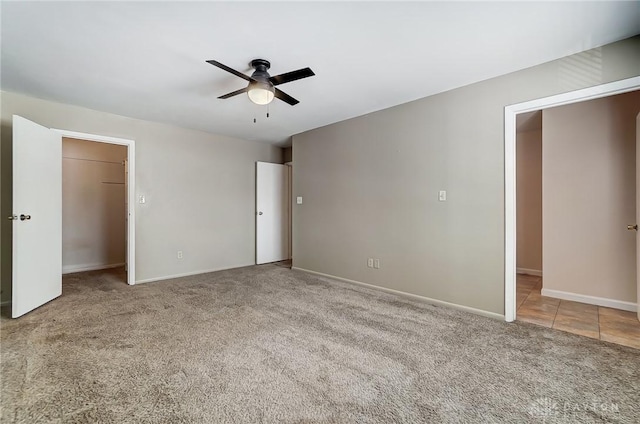 unfurnished bedroom featuring ceiling fan, a walk in closet, a closet, and carpet floors