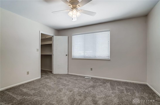 unfurnished bedroom with a spacious closet, ceiling fan, carpet flooring, and a closet