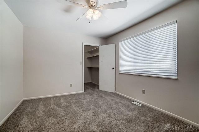 unfurnished bedroom with ceiling fan, a walk in closet, a closet, and carpet floors