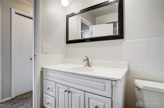 bathroom featuring tile walls, toilet, and vanity