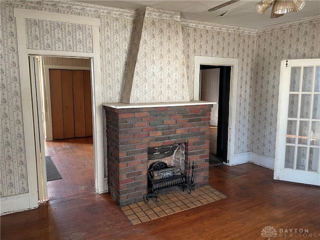 unfurnished living room with a brick fireplace, crown molding, dark hardwood / wood-style floors, and ceiling fan