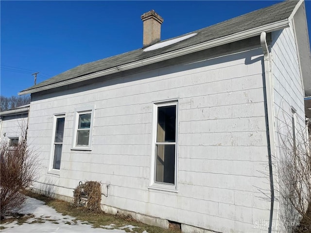 view of side of home featuring a shingled roof and a chimney