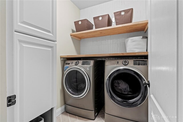 clothes washing area featuring light tile patterned floors and washer and dryer