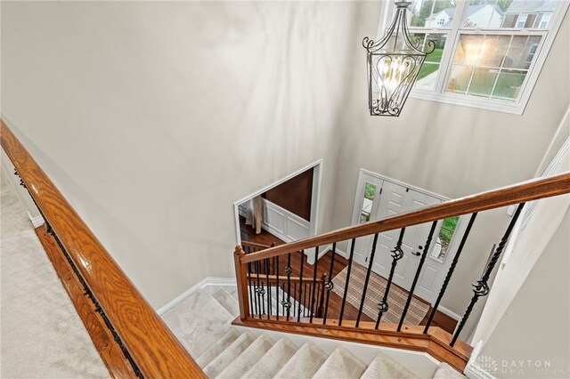 stairs with carpet and a notable chandelier