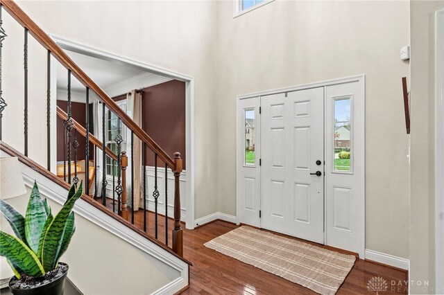 foyer entrance featuring dark hardwood / wood-style floors, ornamental molding, and plenty of natural light