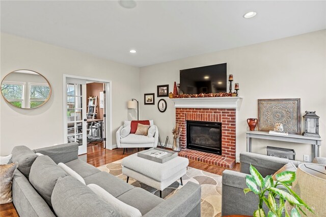 living room with a brick fireplace and light hardwood / wood-style flooring