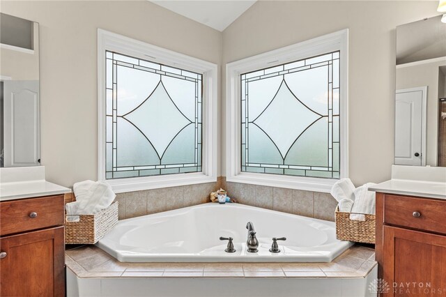 bathroom featuring a healthy amount of sunlight, lofted ceiling, and vanity