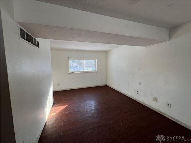 empty room with visible vents and dark wood-type flooring