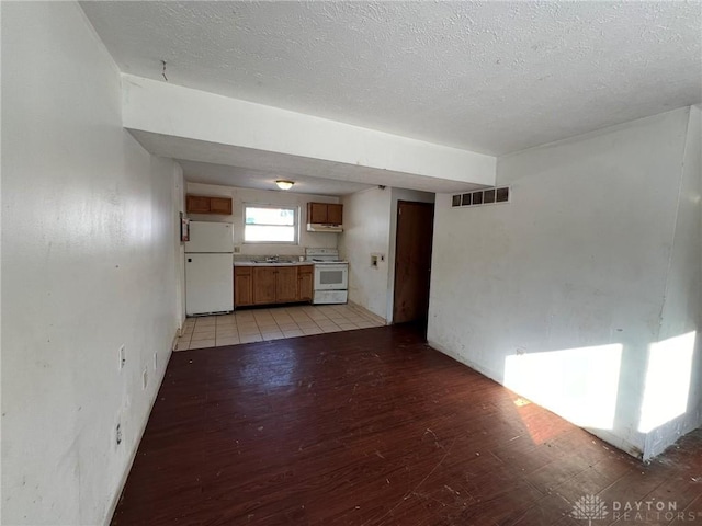 interior space featuring a textured ceiling, light wood-style flooring, a sink, and visible vents