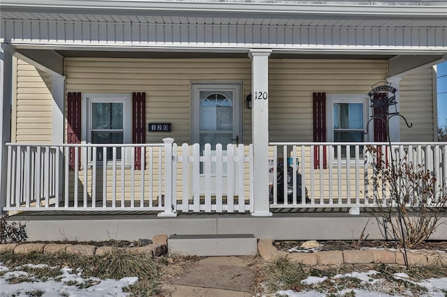 snow covered property entrance featuring covered porch