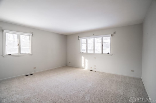 empty room featuring light colored carpet and a wealth of natural light