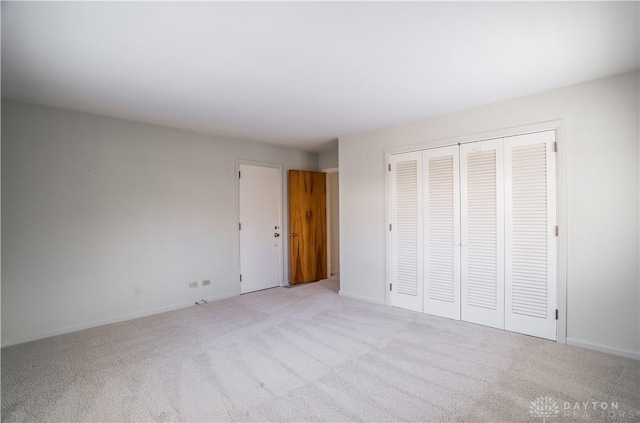 unfurnished bedroom with a closet and light colored carpet