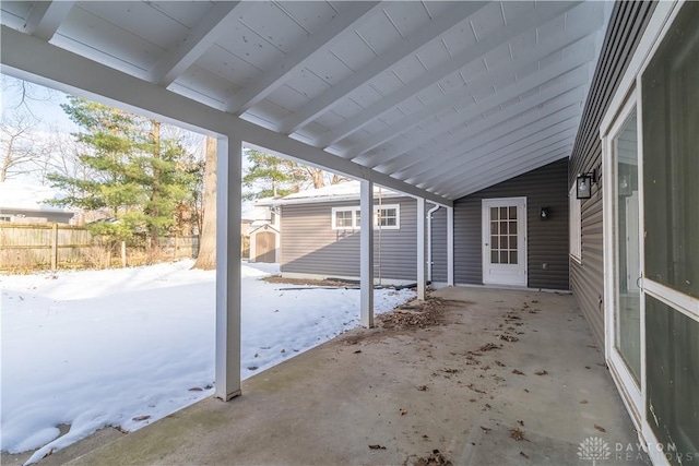 snow covered patio featuring a storage unit