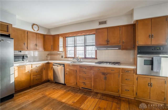 kitchen with decorative backsplash, sink, stainless steel appliances, and light hardwood / wood-style flooring