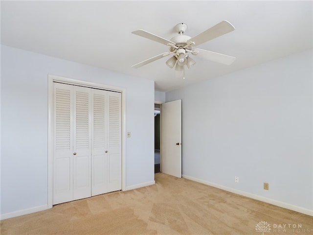 unfurnished bedroom featuring ceiling fan, a closet, and light carpet