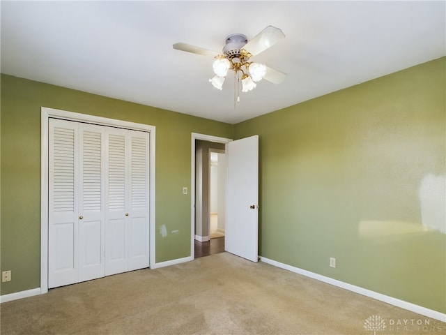 unfurnished bedroom with ceiling fan, a closet, and light carpet