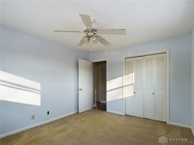 unfurnished bedroom featuring ceiling fan, a closet, and light carpet