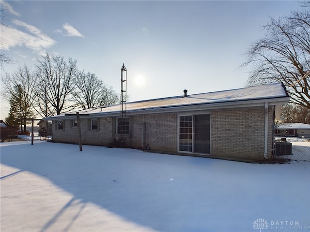 snow covered back of property with central AC