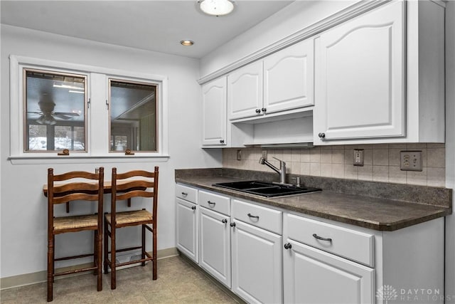 kitchen with decorative backsplash, sink, and white cabinetry