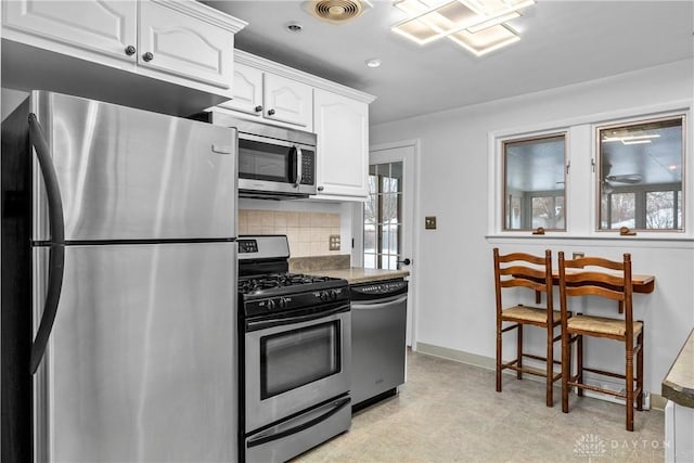 kitchen with white cabinets, decorative backsplash, and stainless steel appliances