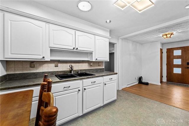 kitchen with white cabinetry, backsplash, and sink