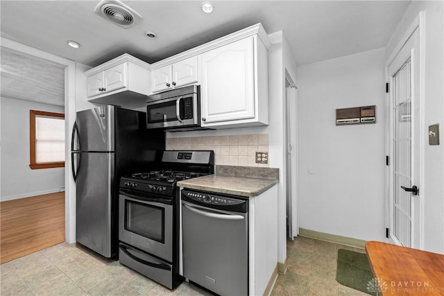 kitchen featuring stainless steel appliances, decorative backsplash, and white cabinets