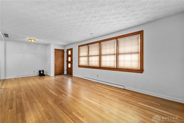 unfurnished room featuring baseboard heating, a textured ceiling, and light hardwood / wood-style flooring