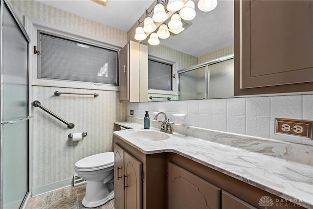 bathroom with a shower with door, toilet, vanity, and tasteful backsplash