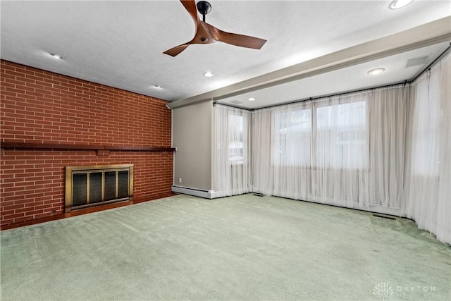 unfurnished living room with brick wall, a textured ceiling, a fireplace, carpet flooring, and ceiling fan