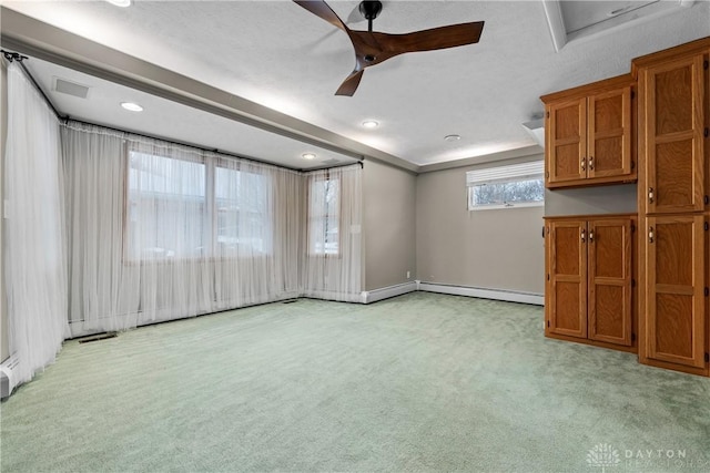 carpeted empty room with ceiling fan, a baseboard radiator, and a tray ceiling