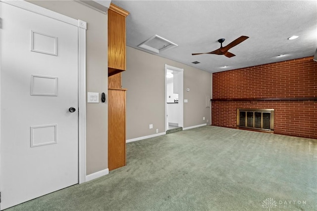 unfurnished living room featuring ceiling fan, brick wall, a fireplace, a textured ceiling, and carpet flooring