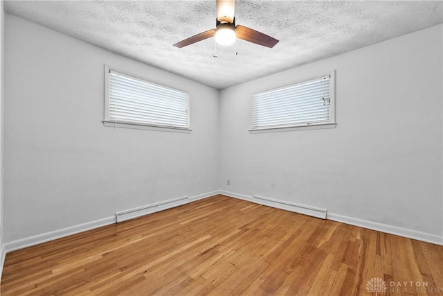 spare room with light wood-type flooring, a textured ceiling, and a baseboard radiator