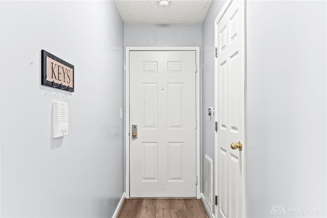 entryway with wood-type flooring and a textured ceiling