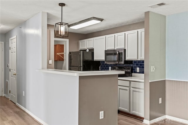 kitchen with electric stove, kitchen peninsula, white cabinetry, and black fridge