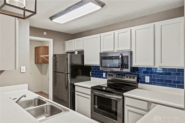 kitchen with a textured ceiling, white cabinets, appliances with stainless steel finishes, tasteful backsplash, and sink