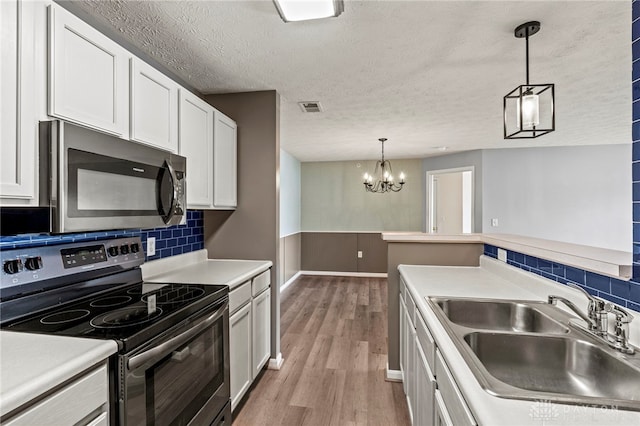 kitchen featuring decorative light fixtures, backsplash, sink, appliances with stainless steel finishes, and white cabinets