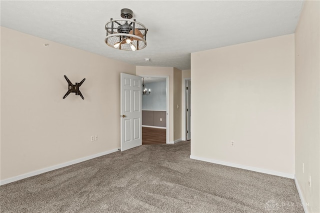 carpeted spare room with an inviting chandelier