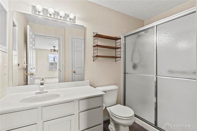 bathroom featuring an enclosed shower, vanity, toilet, and a textured ceiling